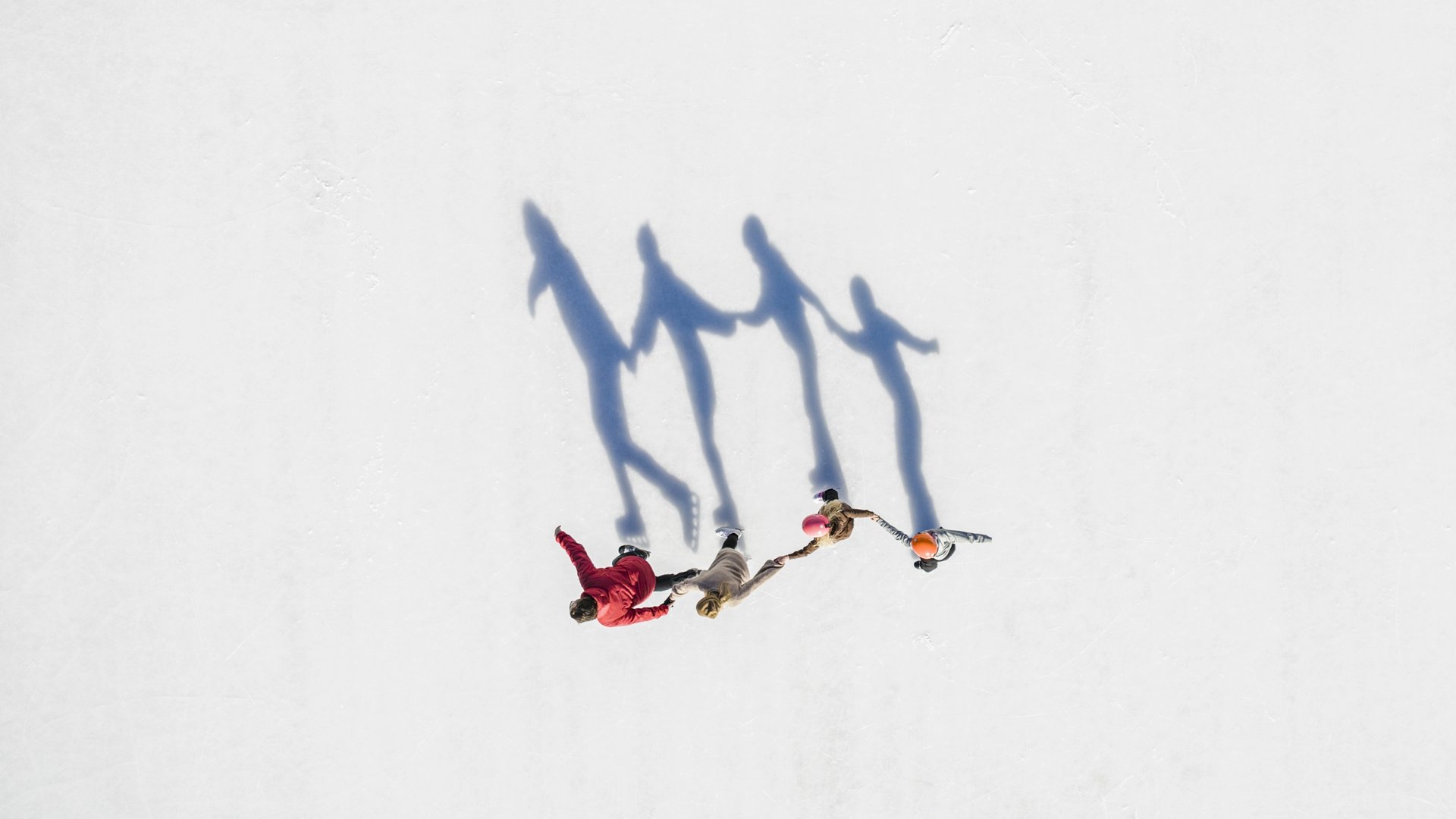 Vogelperspektive einer Familie auf der Eisfläche mit langen Schatten