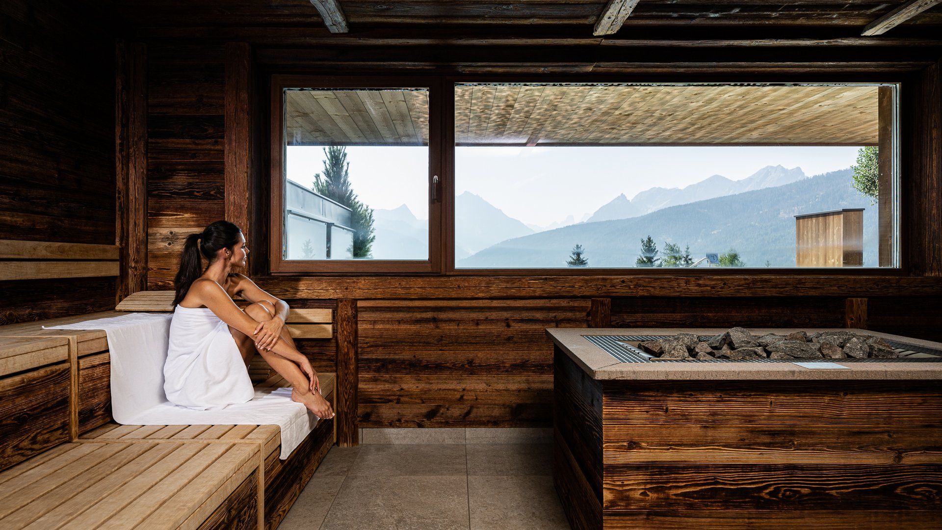 Donna nella sauna con vista sulle montagne da una finestra ampia