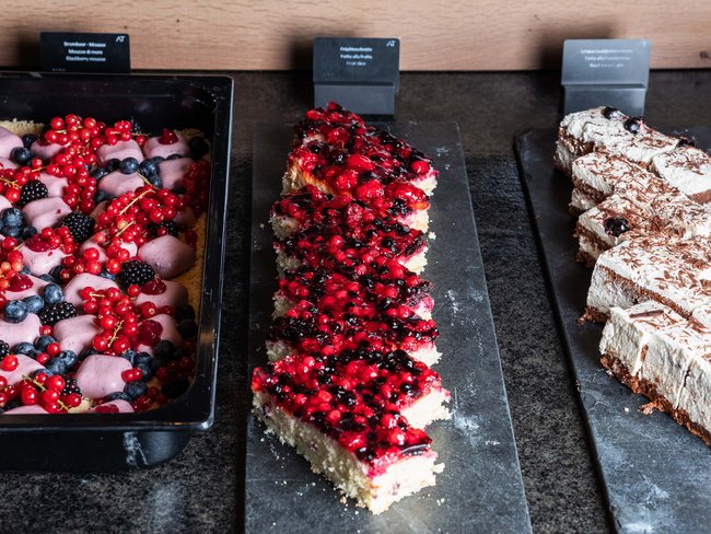 Tre tipi di dolci con frutti di bosco e panna su piatti da portata