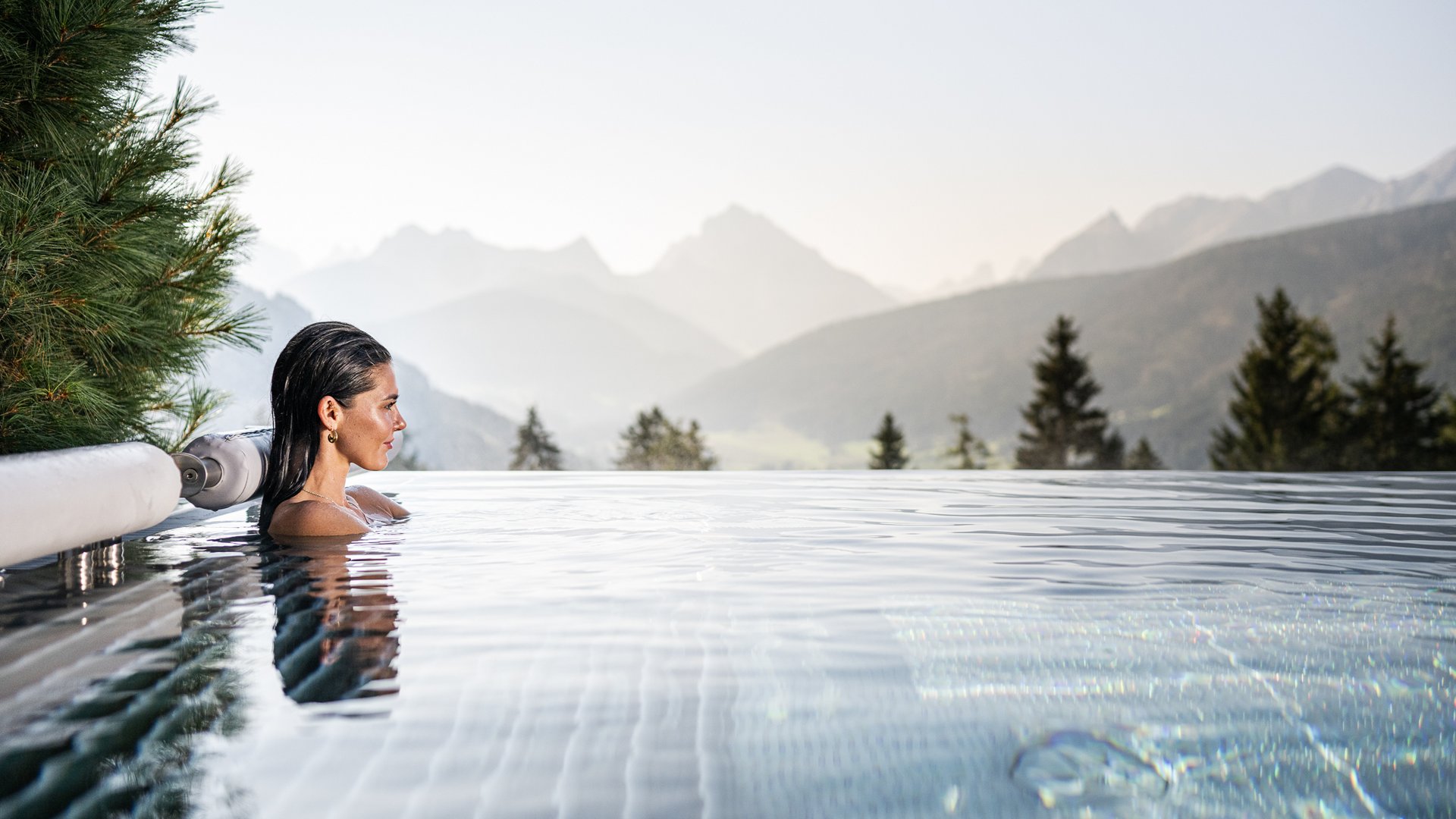 Frau entspannt im Infinity-Pool mit Bergblick