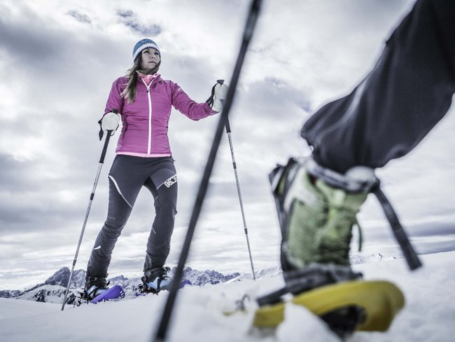Donna che fa escursionismo con racchette da neve in montagna innevata
