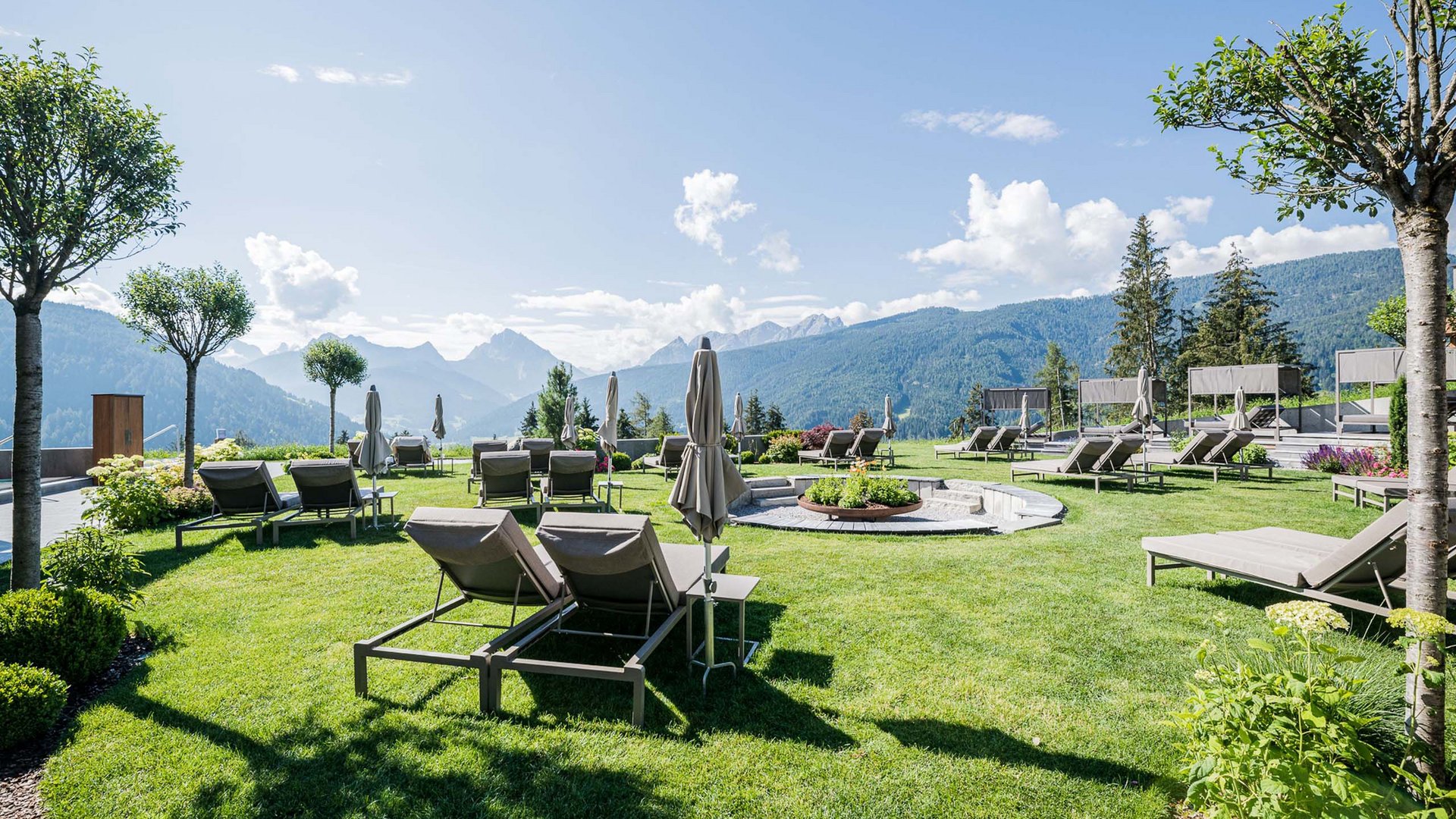 Lounge chairs and umbrellas on green lawn with mountain views