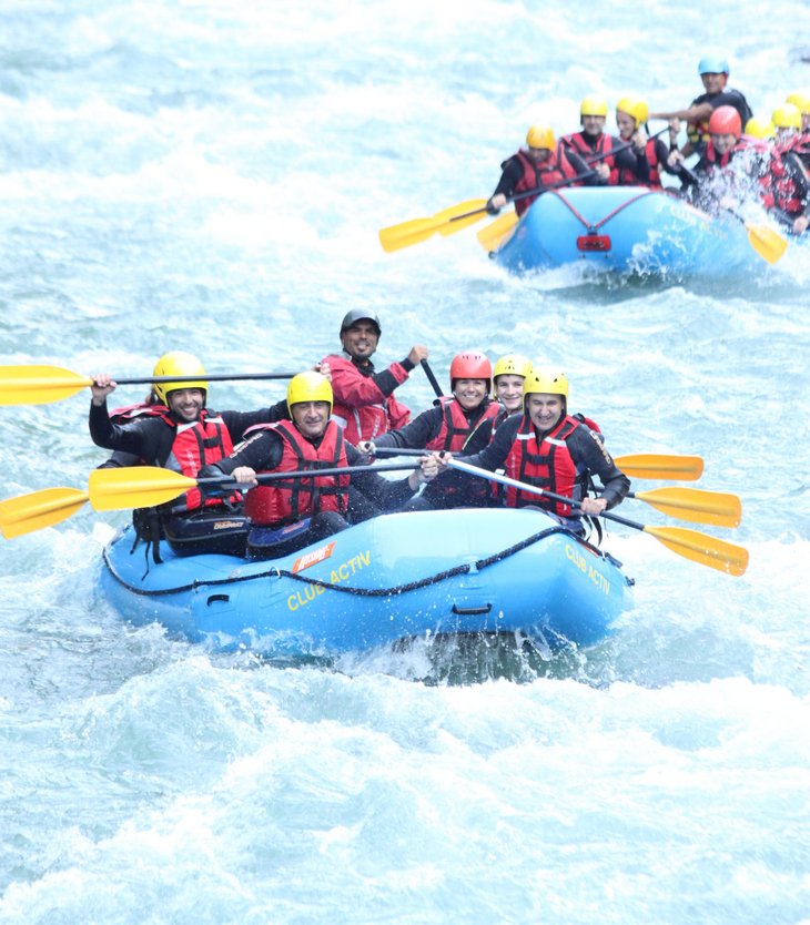 Menschen beim Wildwasser-Rafting auf einem Fluss mit Schutzhelmen und Paddeln