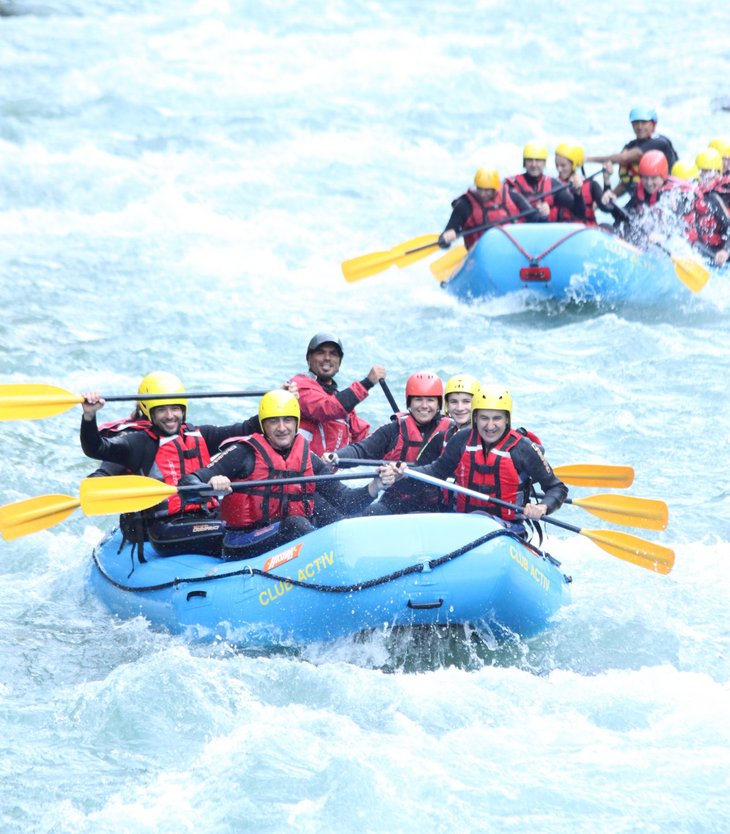 Persone che fanno rafting sul fiume con caschi e pagaie