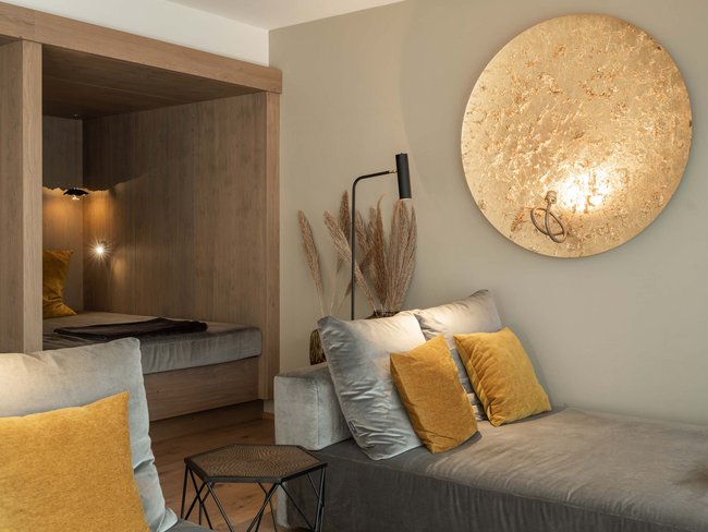 Soggiorno moderno con divano grigio, cuscini gialli e decorazione murale dorata