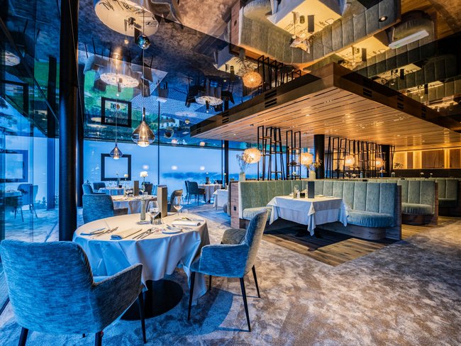 Modernes Restaurant mit blauen Stühlen und großen Fenstern mit Aussicht
