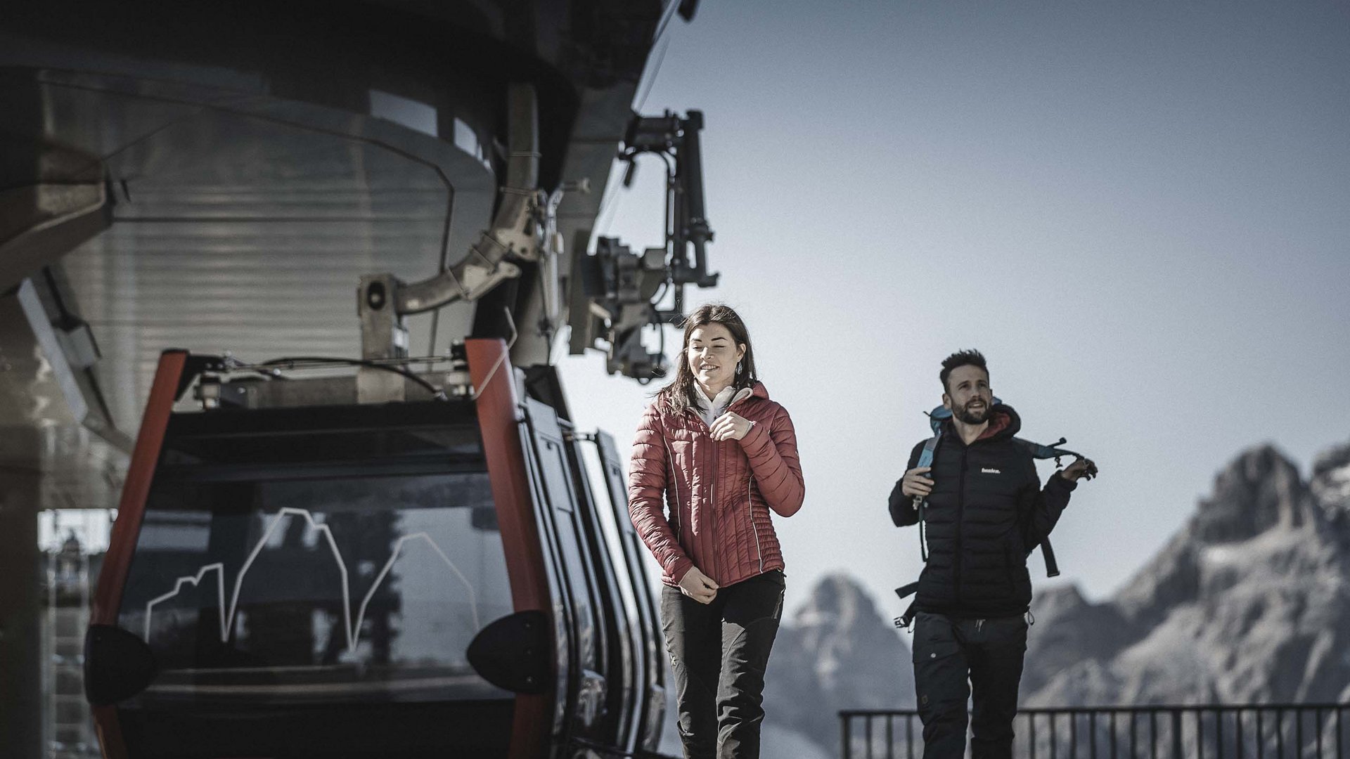 Due escursionisti scendono da una funivia nelle Dolomiti