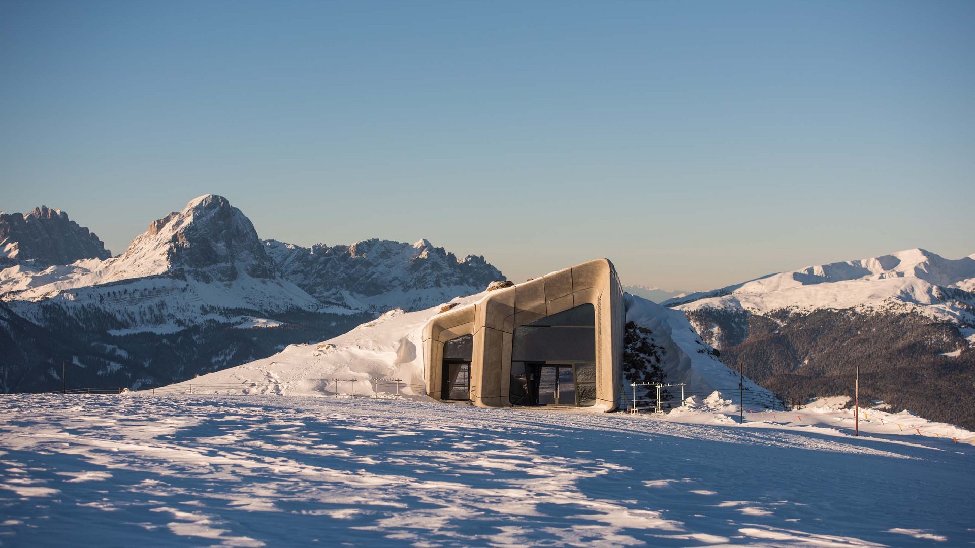 Modern mountain hut in snowy landscape with mountains in background