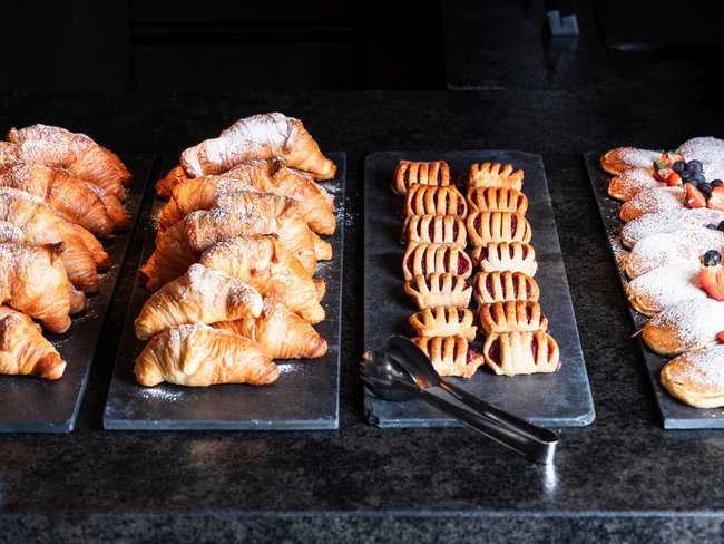 Verschiedene Gebäcksorten wie Croissants und süße Teilchen auf Servierplatten
