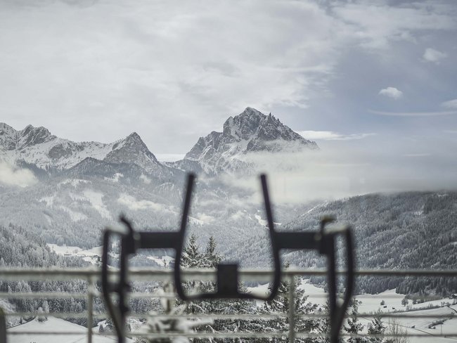 Schneebedeckte Berge mit aufgehängten Stühlen auf einer Terrasse im Vordergrund