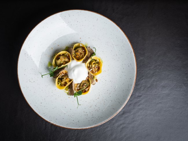 Elegantes Tellergericht mit gefülltem Ravioli und Schaum in der Mitte