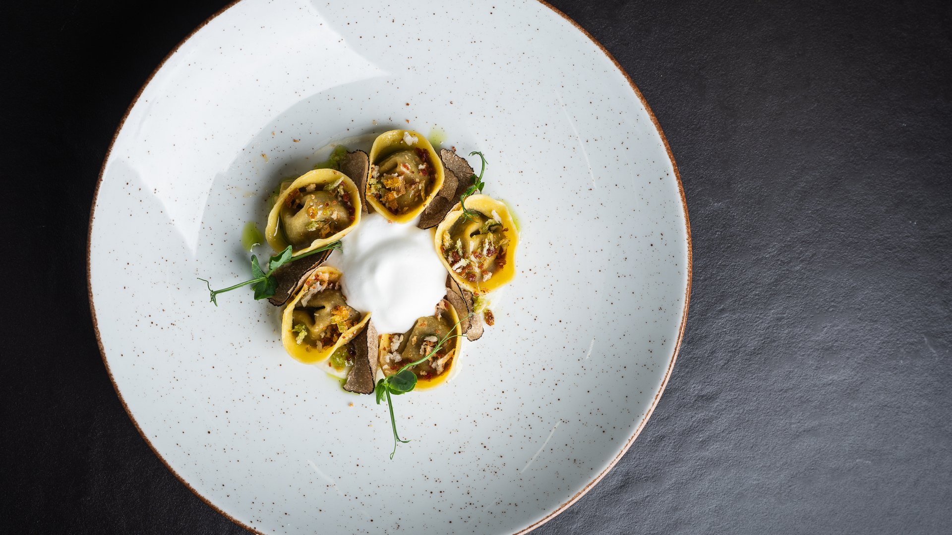 Elegantes Tellergericht mit gefülltem Ravioli und Schaum in der Mitte