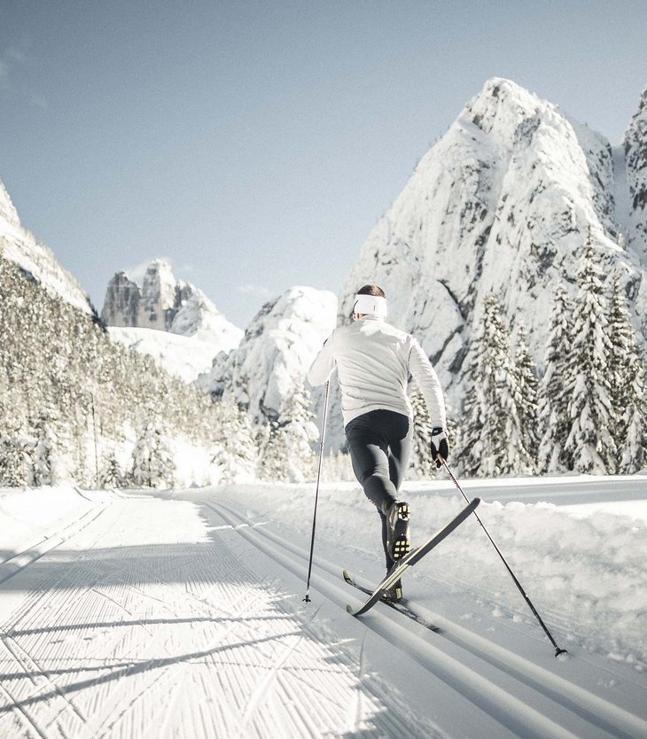 Vacanze invernali in Val Pusteria all’Alpen Tesitin Sciatore di fondo con abbigliamento bianco sulla pista innevata con montagne