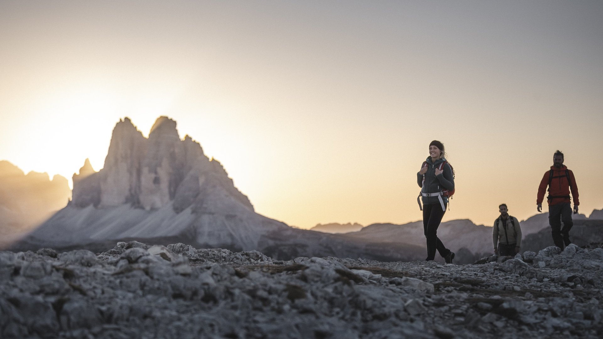 Tre escursionisti al tramonto tra le montagne delle Dolomiti