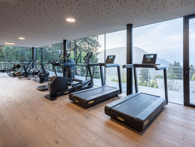 Moderner Fitnessraum mit Laufbändern und Trainingsgeräten vor Panoramafenstern