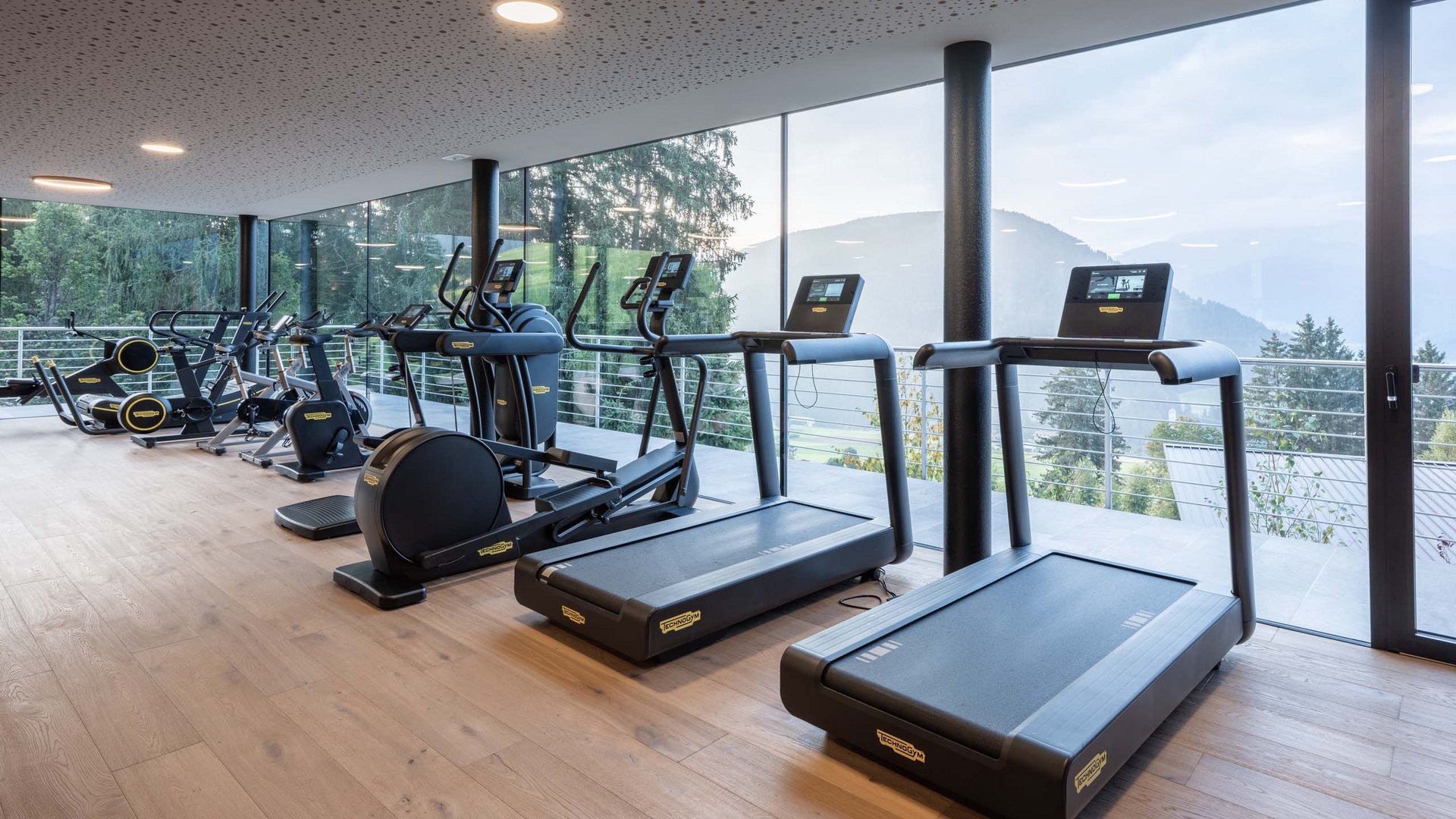 Moderner Fitnessraum mit Laufbändern und Trainingsgeräten vor Panoramafenstern