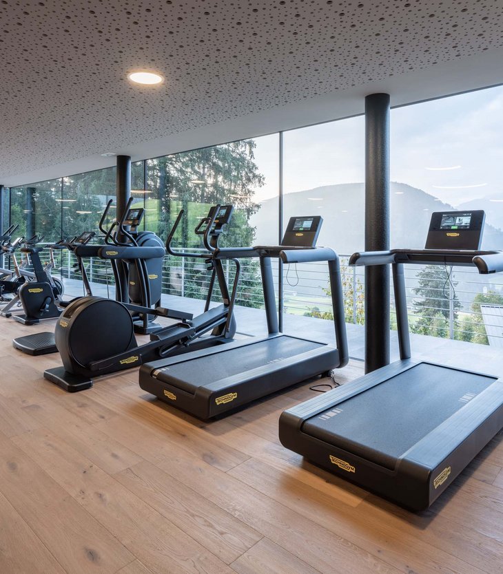 La vostra vacanza wellness esclusiva da Belvita Palestra moderna con tapis roulant e attrezzi davanti a grandi finestre panoramiche