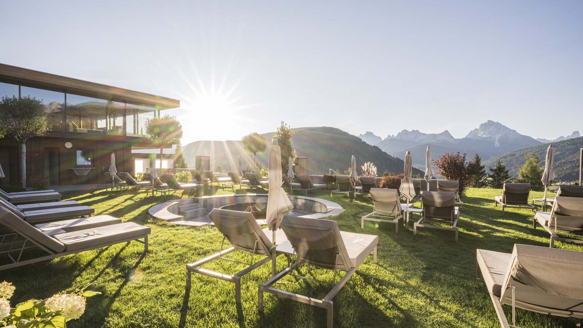 Alba sulle montagne con lettini in giardino di un hotel