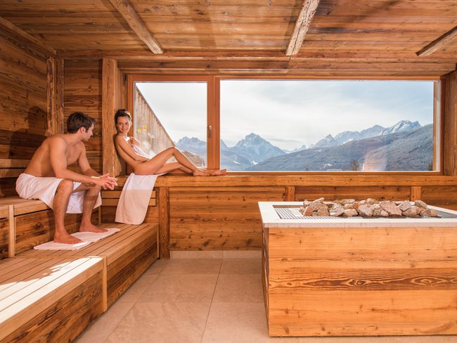 Coppia rilassata in sauna con vista sulle montagne dalla finestra grande