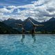 Zwei Frauen machen Handstände am Pool vor Berglandschaft