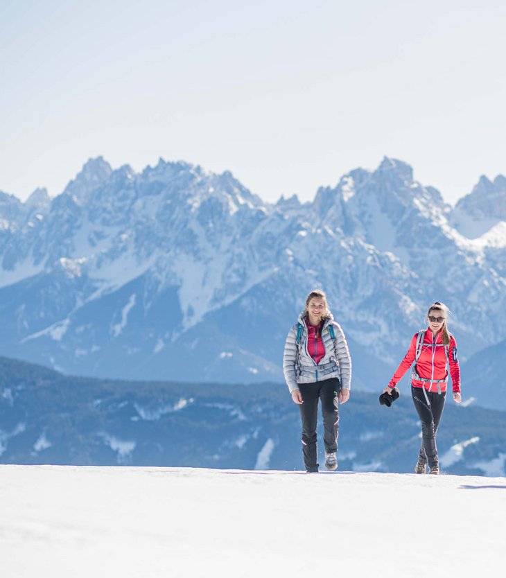 Vacanze invernali in Val Pusteria all’Alpen Tesitin Tre donne che camminano sulla neve con montagne sullo sfondo