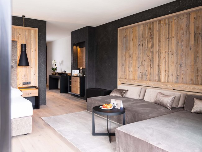 Zona salotto moderna in camera d'hotel con divano, tavolo e parete in legno