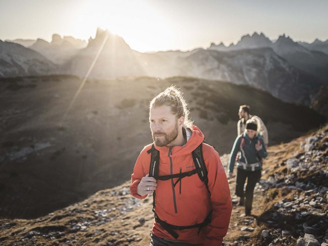 Escursionisti con giacca rossa su sentiero di montagna al tramonto