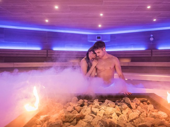 Hotel con vasca idromassaggio in camera in Trentino-Alto Adige Coppia che si rilassa in una sauna fumante con pietre e fuoco