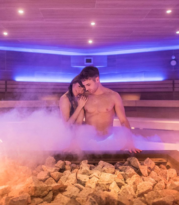 Alpen Tesitin: Ihr Wellnesshotel im Pustertal Paar entspannt in einer dampfenden Sauna mit Feuer und Steinen