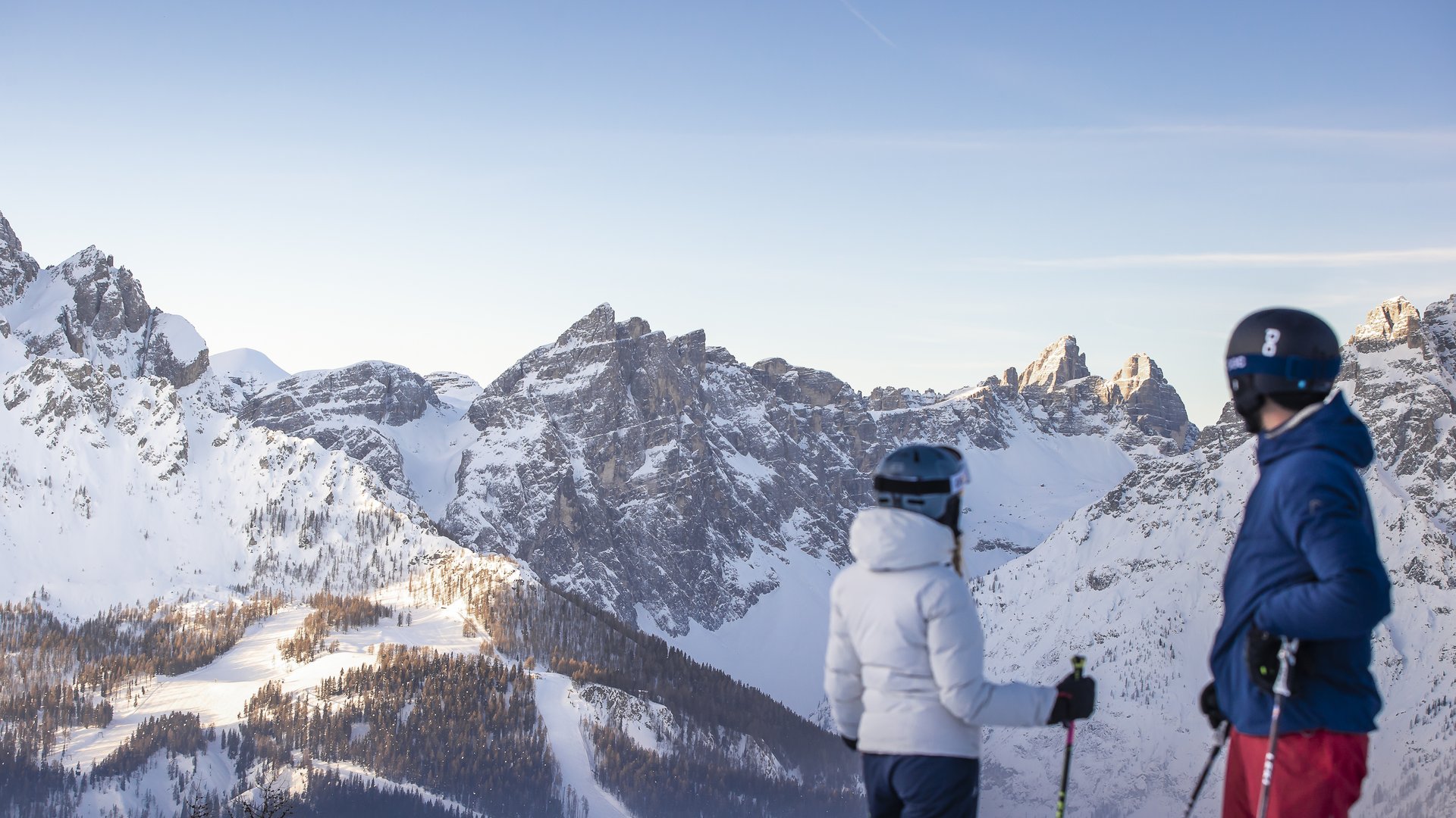 Due sciatori guardano le montagne innevate con cielo limpido