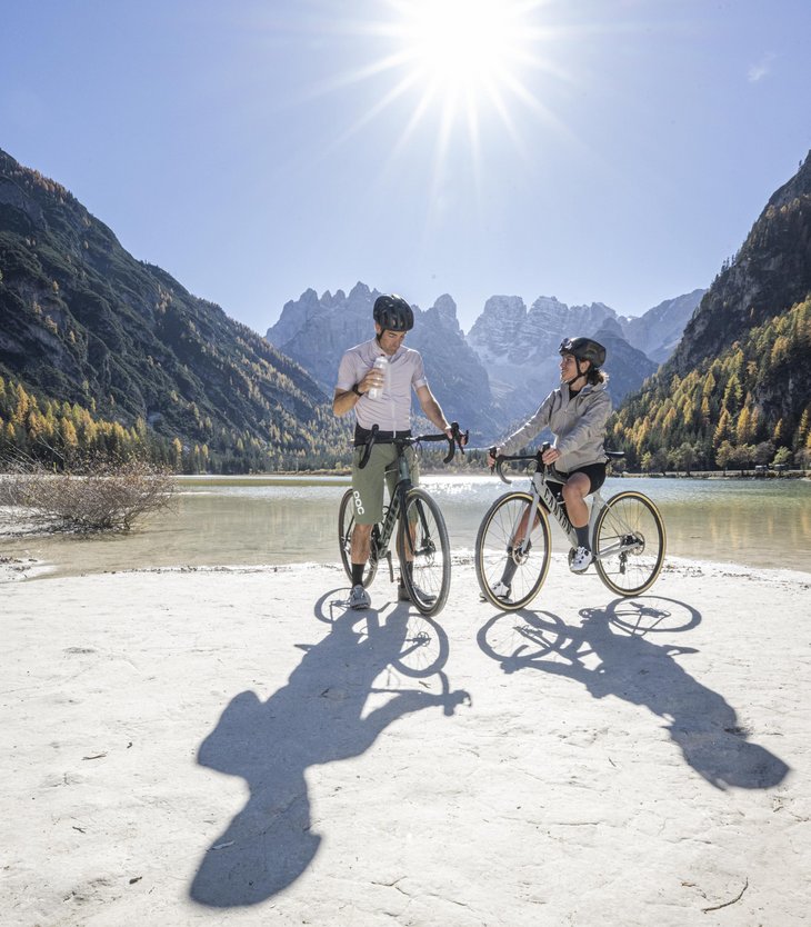 Zwei Radfahrer stehen am See in den Bergen bei sonnigem Wetter