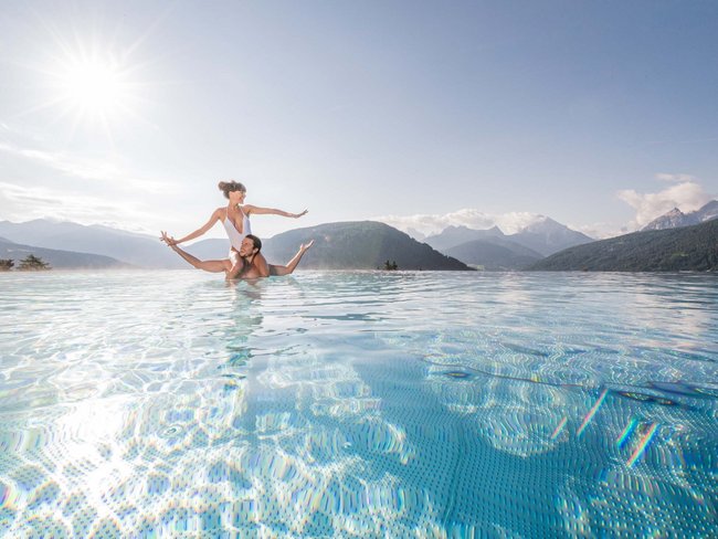 Paar genießt Sonnenschein in einem Pool mit Bergblick