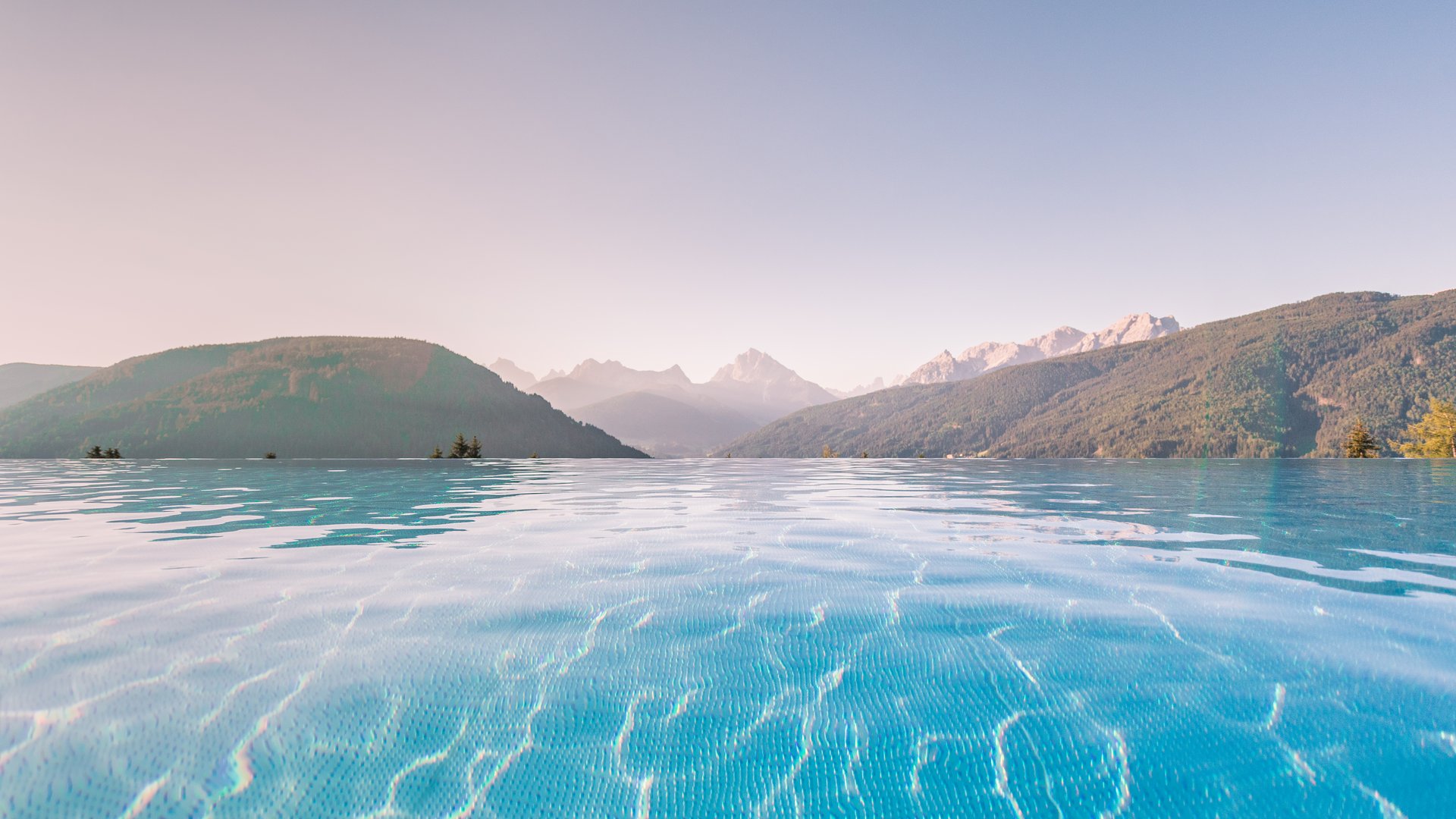 Piscina a sfioro con vista su montagne boschive e cielo limpido
