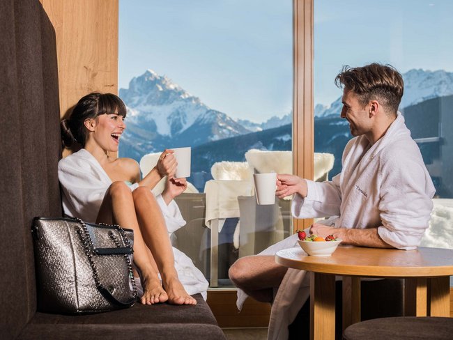 Alpen Tesitin: Ihr Wellnesshotel im Pustertal Paar in Bademänteln trinkt Kaffee mit Bergblick im sonnigen Zimmer