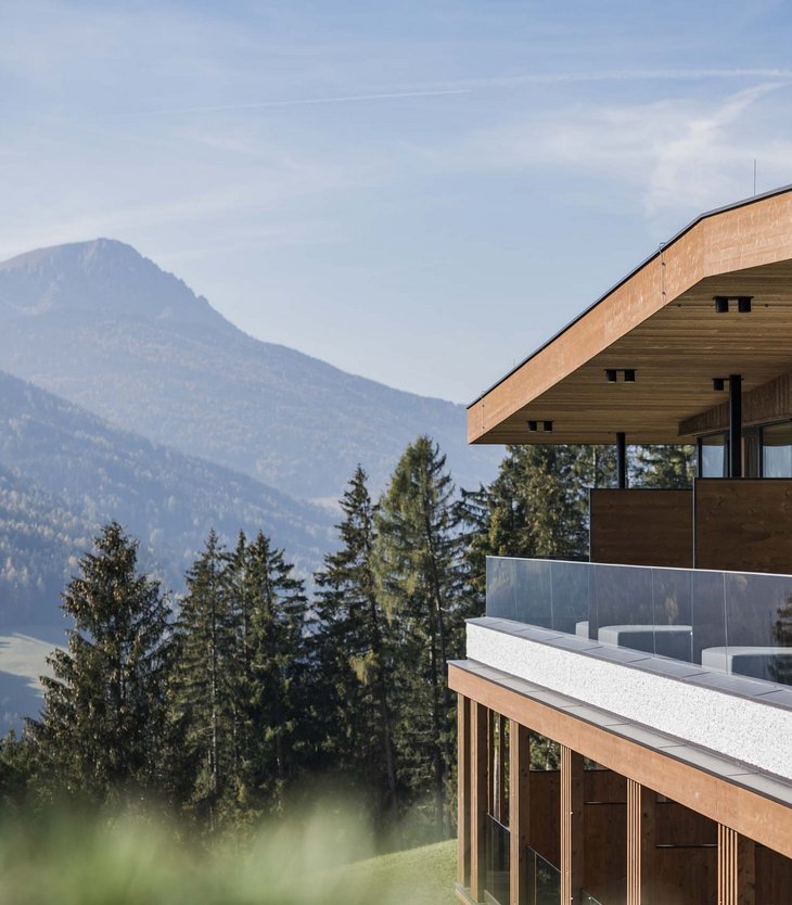Your 5-star hotel in Val Pusteria/Pustertal: Alpen Tesitin Modern wooden building balcony with glass railing overlooking forest and mountains