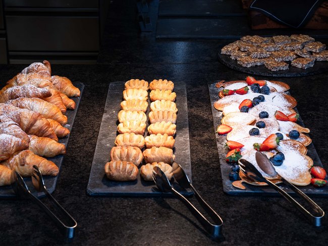 Varie pasticcerie e pancake con frutta su piatti neri da portata