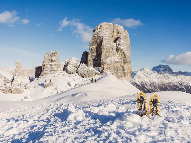 Secrets Racchette da neve nella neve con rocce delle Dolomiti sotto un cielo blu