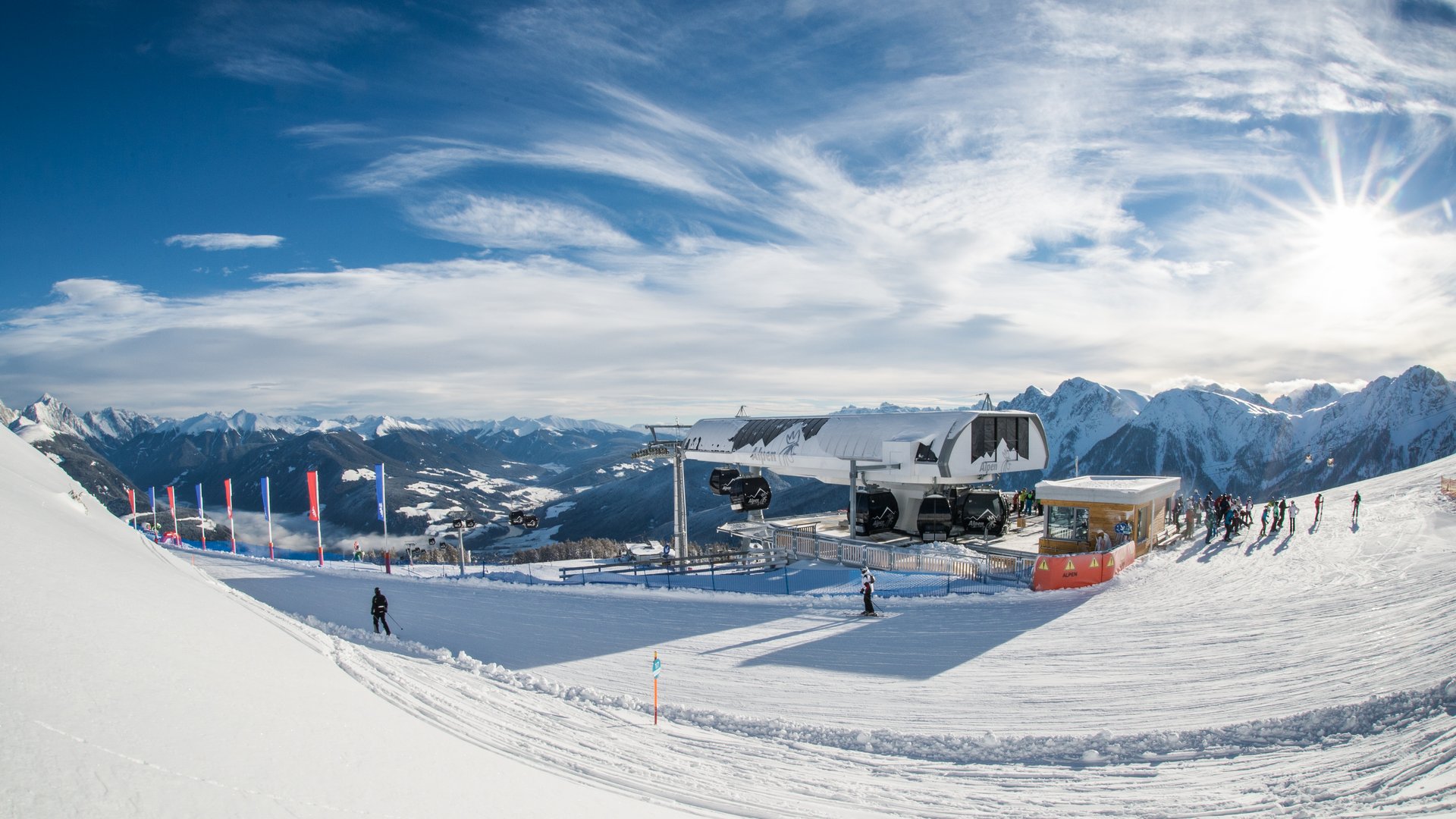 Stazione della cabinovia con sciatori e montagne innevate sullo sfondo
