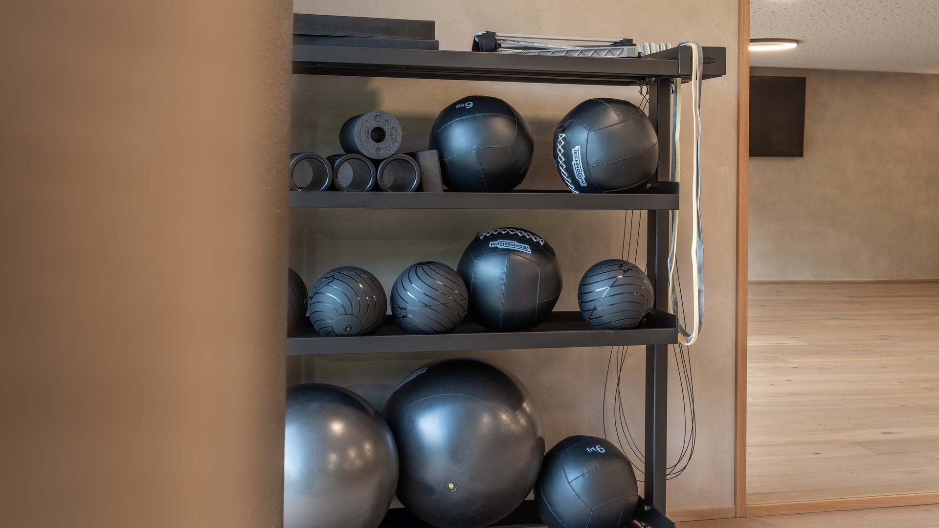 Schwarze Gymnastikbälle und Rollen auf einem Regal in einem Fitnessraum