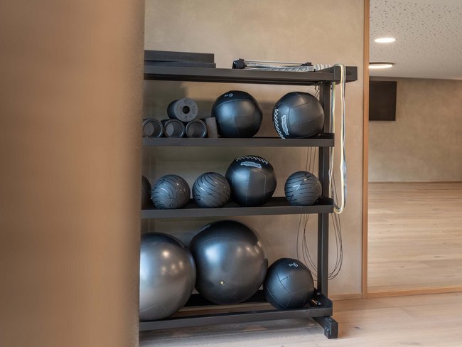 Schwarze Gymnastikbälle und Rollen auf einem Regal in einem Fitnessraum