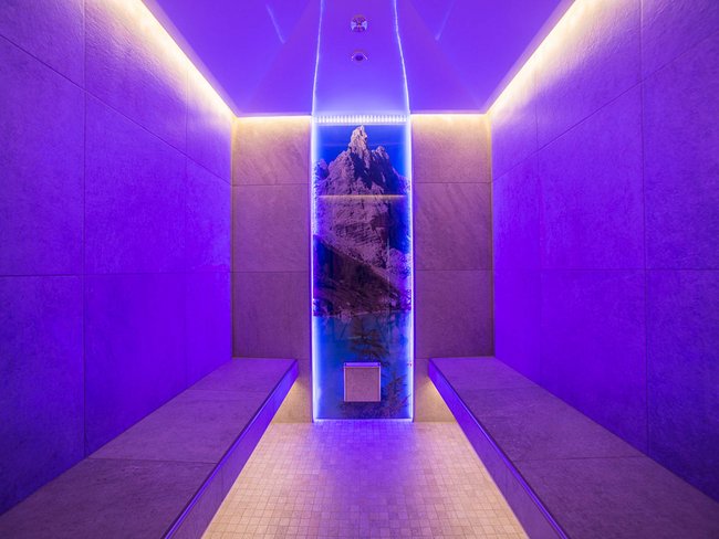 Sala benessere moderna con illuminazione LED blu e motivo montano sulla parete