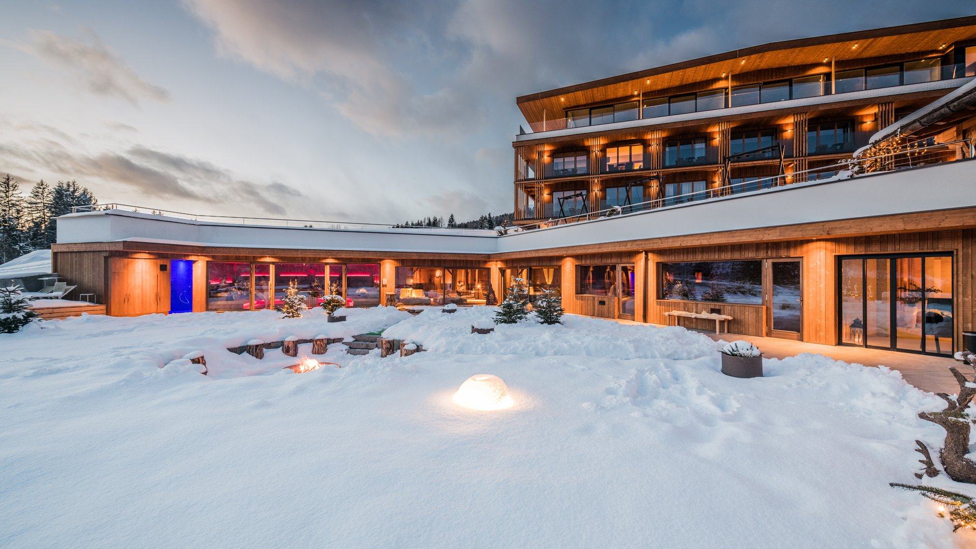 Hotel con sauna in Alto Adige:l’Alpen Tesitin Hotel moderno nella neve al crepuscolo con luci calde