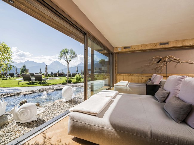 Lounge confortevole con vista su giardino, montagne e fontana d'acqua