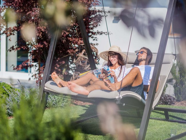 Couple relaxing on a swing in the garden on a sunny day