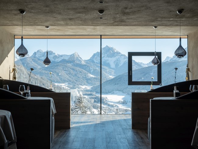 Restaurant mit großer Glasscheibe und Blick auf verschneite Berge und Tal