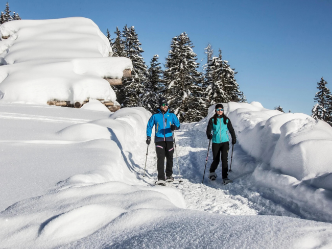 Secrets Due persone che fanno escursionismo con racchette da neve su un sentiero innevato