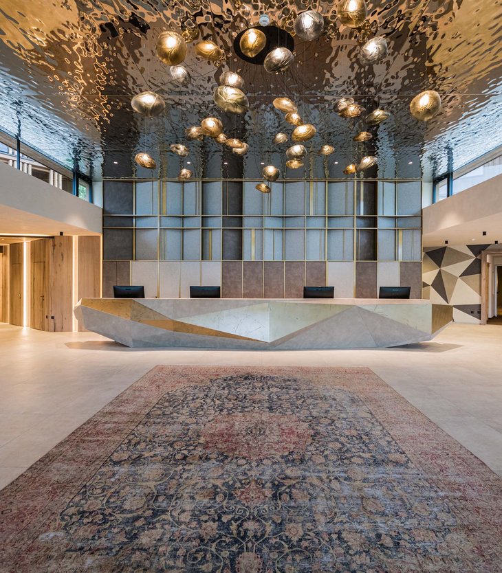 La vostra vacanza wellness esclusiva da Belvita Area reception moderna con bancone geometrico e lampade scultoree al soffitto
