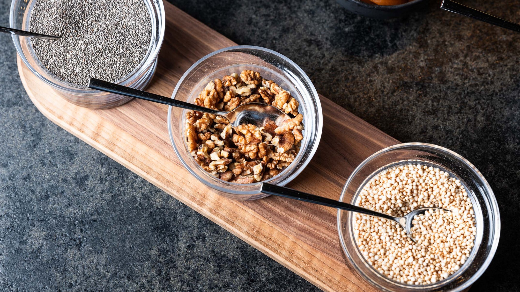 Alpen Tesitin: Ihr Gourmethotel in Südtirol Schalen mit Chiasamen, Walnüssen und Quinoa auf einem Holzbrett