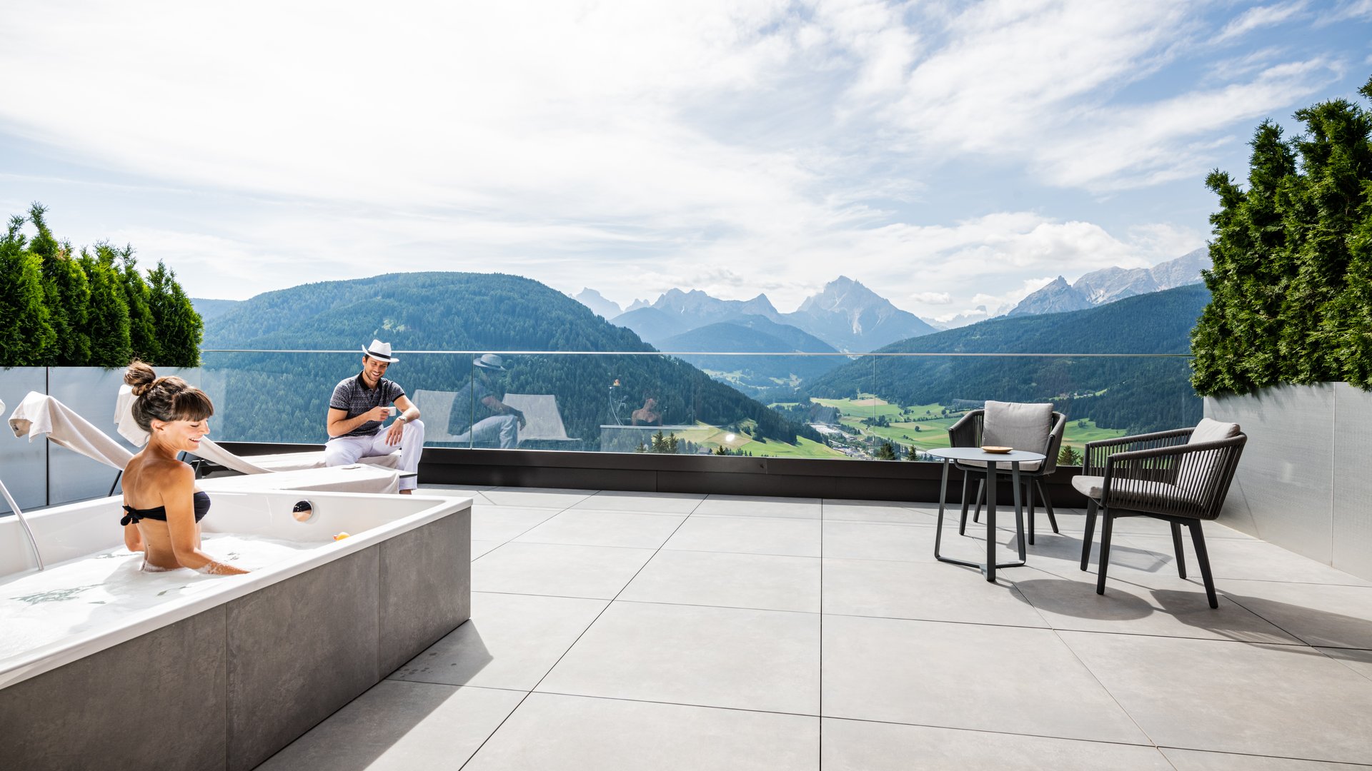 Persone si rilassano su terrazza con vasca idromassaggio e vista montagna