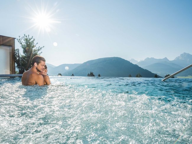 Paar entspannt in Whirlpool mit Bergpanorama und Sonnenschein